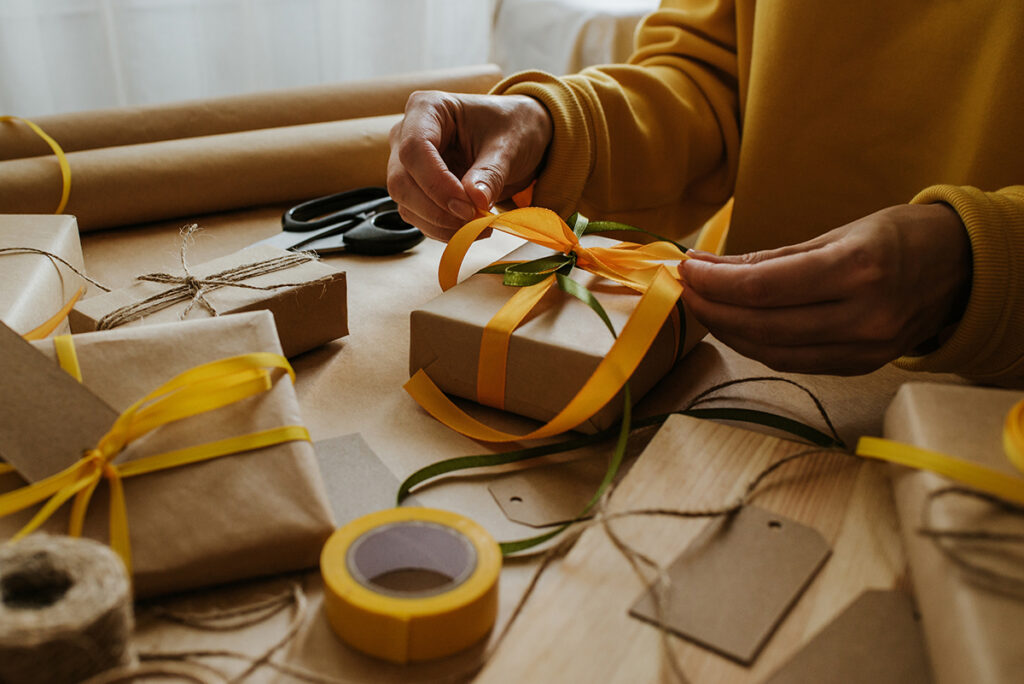 Woman packaging a gift with wrapping paper and natural twine.