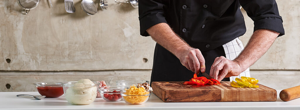 Private chef cutting red pepper, preparing meal at home